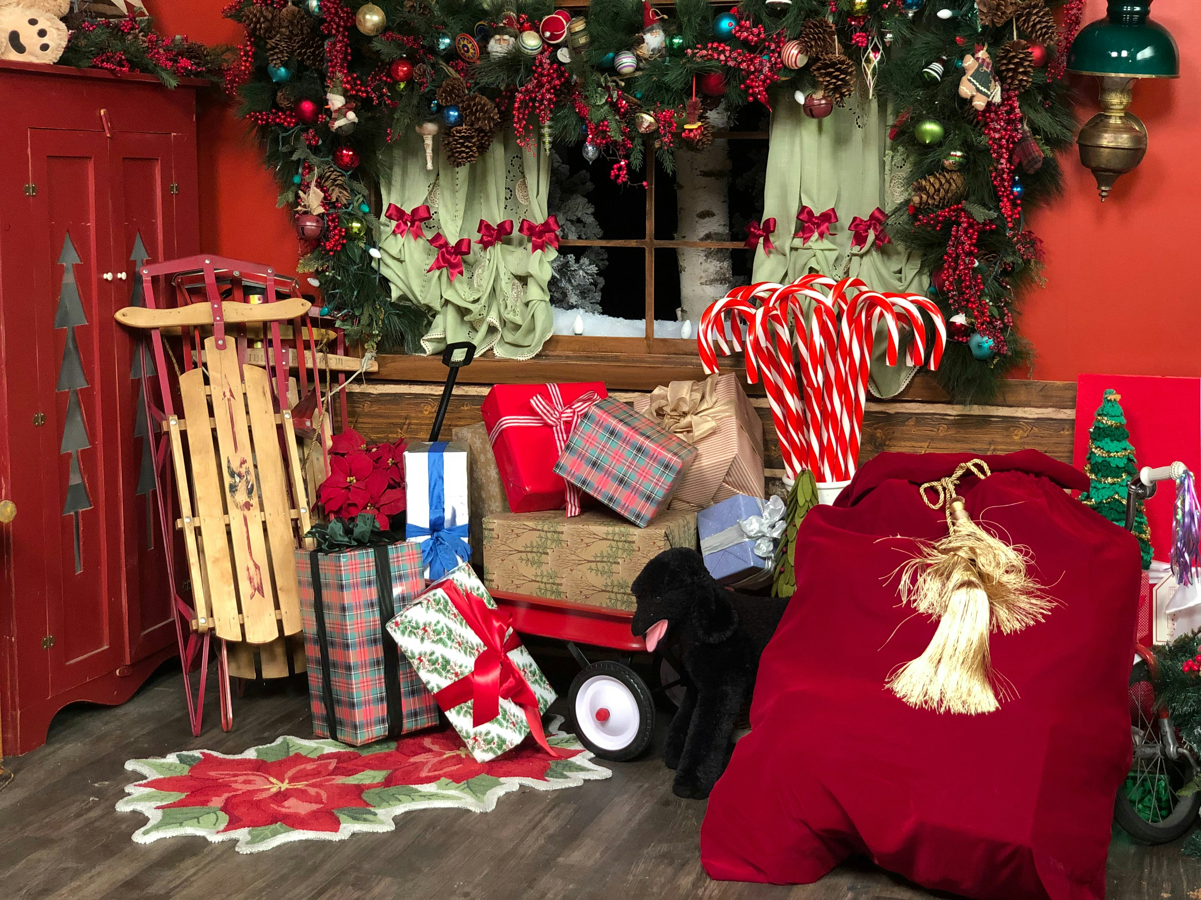 Wrapped and bagged Christmas gifts in a room with many Christmas decorations.