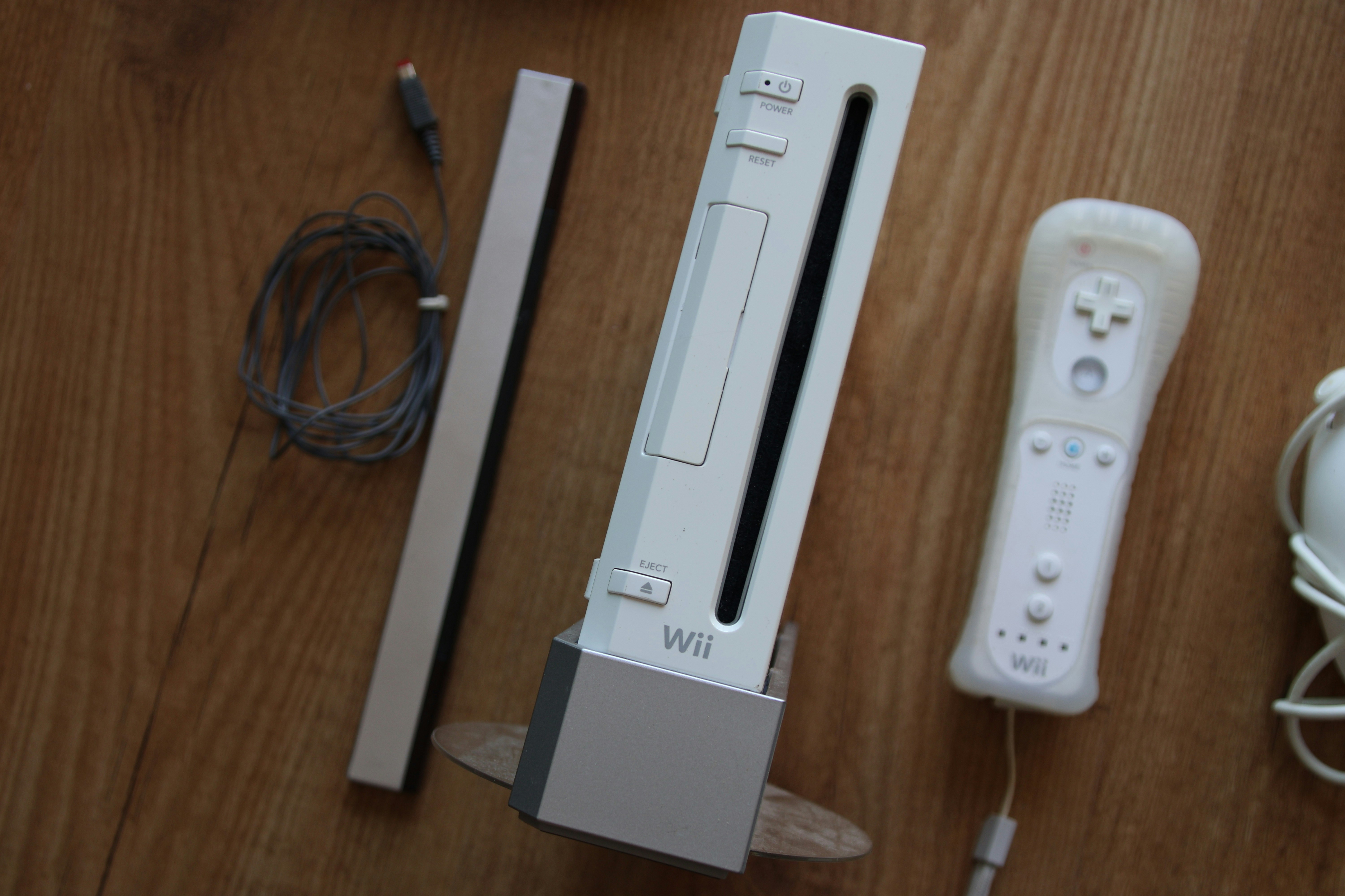 Nintendo Wii and one Wii remote on a wood table.